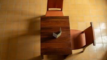 Una mesa de madera con una silla, una cómoda pequeña y un suelo de baldosas.