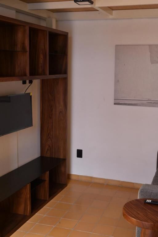Een kamer met een ingebouwde houten plankkast, een flatscreen televisie en een klein rond tafeltje.