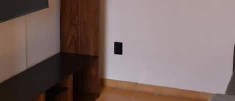 Een kamer met een ingebouwde houten plankkast, een flatscreen televisie en een klein rond tafeltje.