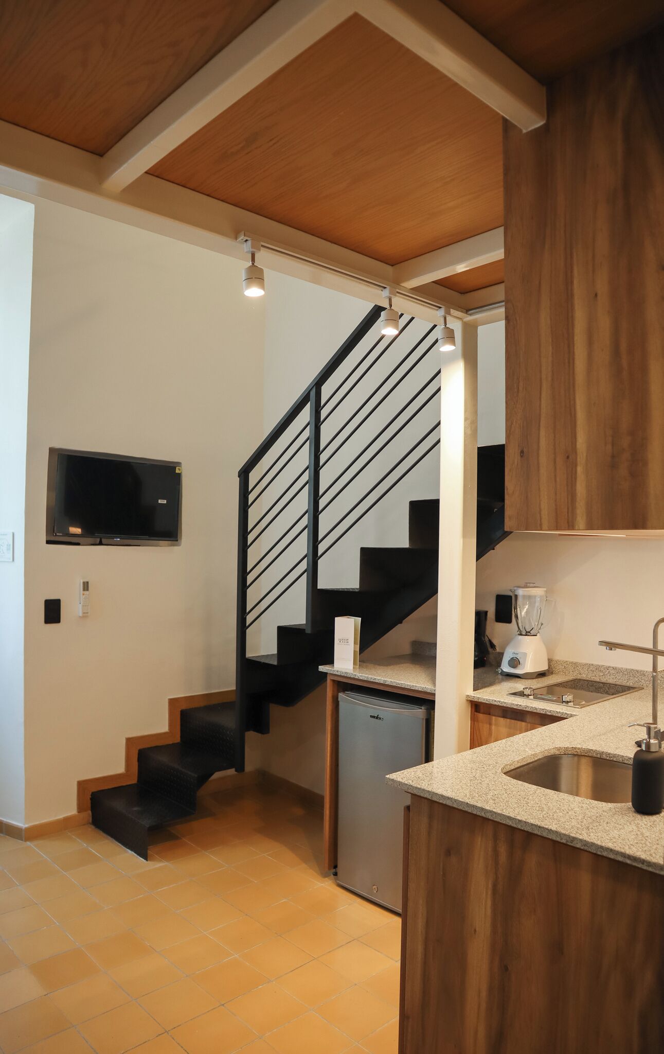 A kitchen with a built-in dishwasher, a blender, a microwave, and a wooden cabinet.