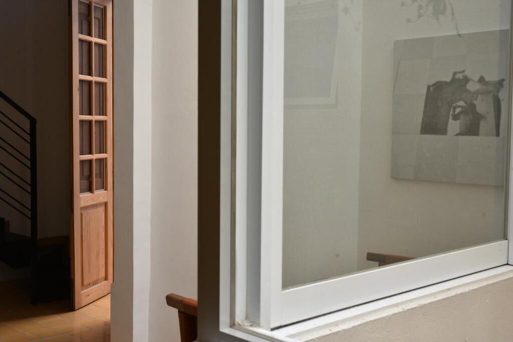 Una habitación con un gran ventanal, una puerta de madera y una escalera.