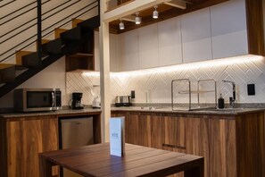 A modern kitchen with a herringbone tile backsplash, stainless steel appliances, and a wooden dining table. - Lopez Cotilla 658 (Guadalajara)