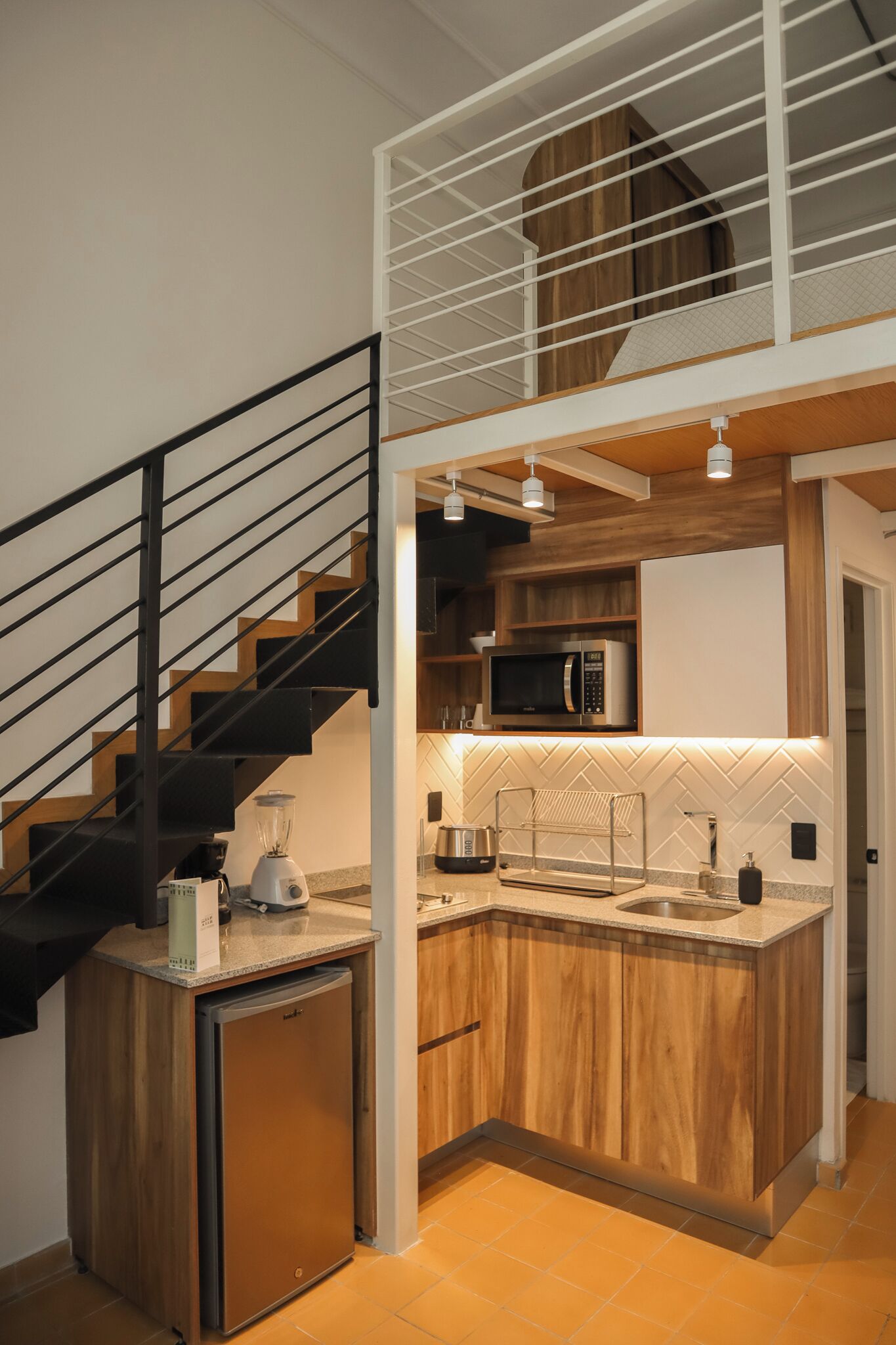 Una cocina compacta con microondas integrado, cafetera y pileta.