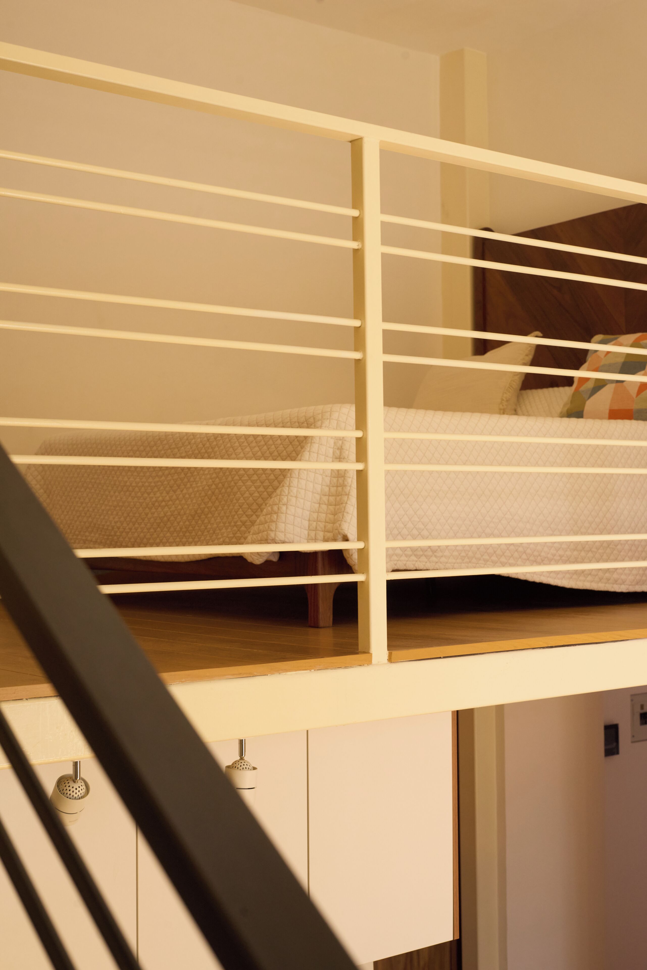 Una cama litera con estructura blanca y un somier inferior con colchón acolchado.
