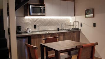 Una cocina compacta con microondas, licuadora y un salpicadero con diseño de espiga.