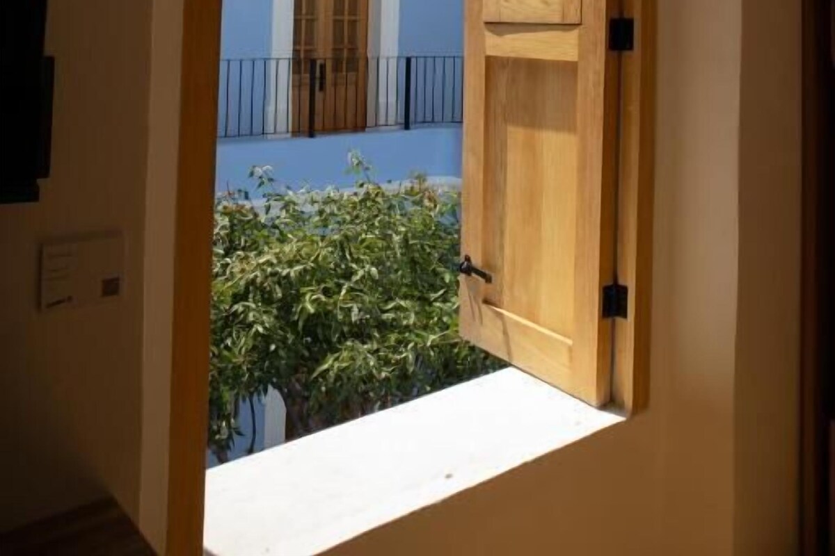 A wooden door leading to a balcony with a blue wall and a window.