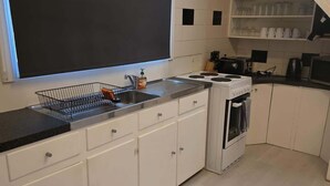Una cocina moderna con armarios blancos, encimera negra, horno empotrado y pileta.