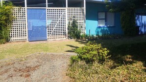 Una casa de dos pisos con fachada azul, un patio delantero cercado y un camino de entrada de grava.
