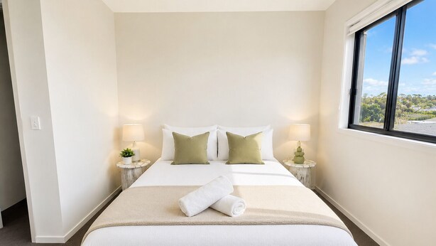 A hotel room with a large bed, two bedside tables with lamps, a window with a view, and a carpeted floor. - The Sunny Nook - 20 mins to BNE CBD (Coopers Plains)