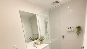 A modern bathroom with a toilet, a sink, a shower, and a mirror. - The Sunny Nook - 20 mins to BNE CBD (Coopers Plains)