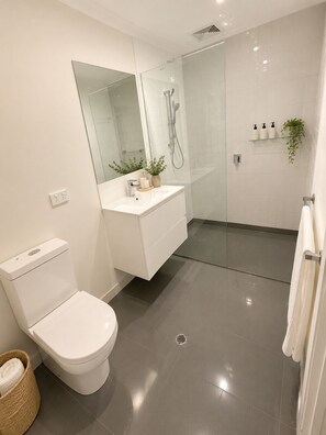 A modern bathroom with a toilet, a sink, a shower, and a mirror. - The Sunny Nook - 20 mins to BNE CBD (Coopers Plains)