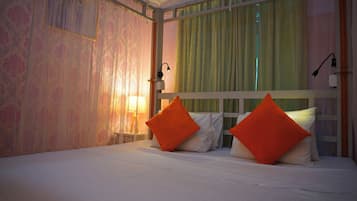 Habitación de hotel con cama, dos almohadas, mesita de noche, lámpara y ventana con cortinas.