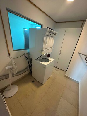 A compact laundry room with a washing machine, dryer, and a small fan. - Spacious 3BR Marina Condo Near Cancun Hotel Zone (Cancun)