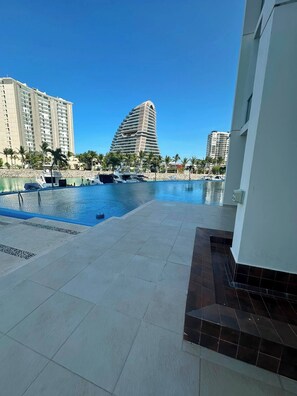 A swimming pool area with a modern building in the background. - Spacious 3BR Marina Condo Near Cancun Hotel Zone (Cancun)
