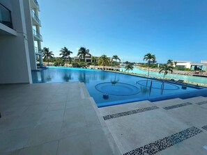A swimming pool with a view of a marina and palm trees. - Spacious 3BR Marina Condo Near Cancun Hotel Zone (Cancun)