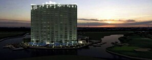 A high-rise hotel with a pool and a golf course in the background. - Spacious 3BR Marina Condo Near Cancun Hotel Zone (Cancun)