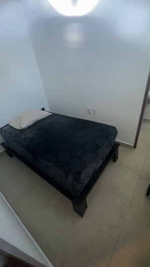 A small, single-bed room with a dark patterned bedspread, a white pillow, and a plain white wall. - Spacious 3BR Marina Condo Near Cancun Hotel Zone (Cancun)
