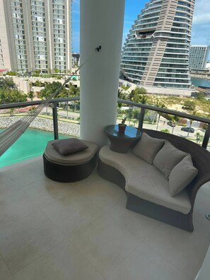 A balcony with a sofa, a small table, and a hammock. - Spacious 3BR Marina Condo Near Cancun Hotel Zone (Cancun)