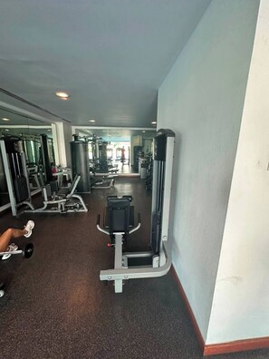 A gym with various exercise machines, a weight bench, and a mirror on the wall. - Spacious 3BR Marina Condo Near Cancun Hotel Zone (Cancun)