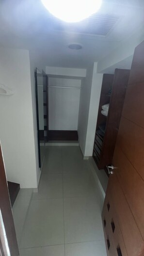 A narrow hallway with a tiled floor, a door on the right, and a closet with a hanging rod on the left. - Spacious 3BR Marina Condo Near Cancun Hotel Zone (Cancun)