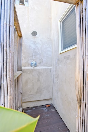 Ein schmales, abgetrenntes Duschbad mit Brausekopf aus Metall und einem Fenster an der Seite.