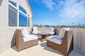 Eine Terrasse im Freien mit Korbmöbeln und einem runden Tisch.