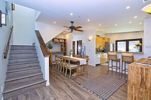 Eine moderne Küche mit Holzschränken, einer zentralen Kücheninsel und einem Essbereich mit Tisch und Stühlen.