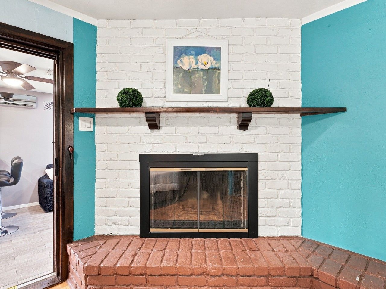 A fireplace with a white brick surround, a black screen door, and a teal wall.