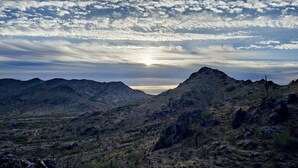 Paisaje montañoso con cielo despejado y el sol poniéndose o saliendo.