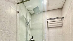 Un baño moderno con ducha de mampara, inodoro y toallero.