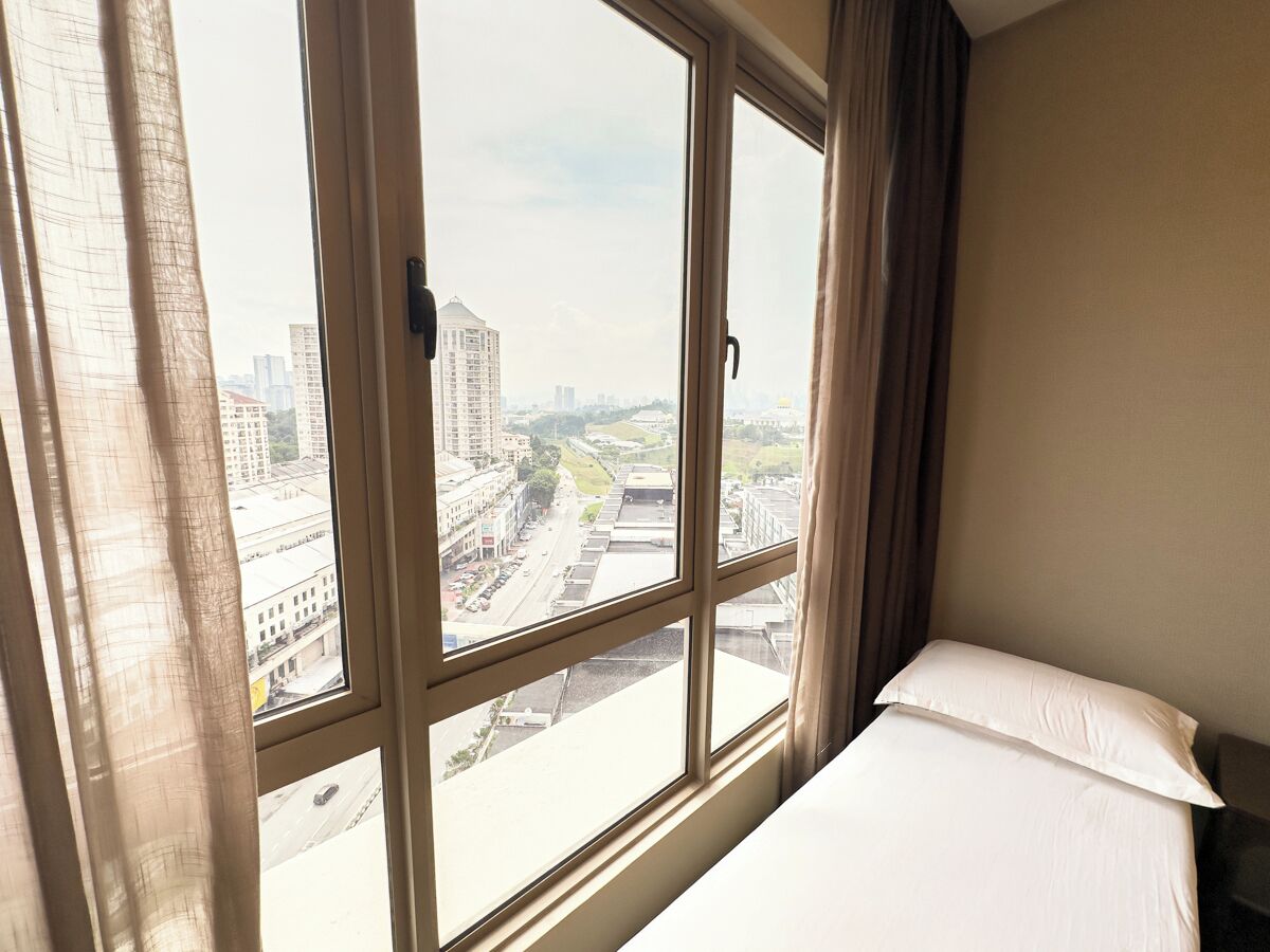 A hotel room with a large window, a bed, and curtains.