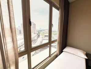 Una habitació d'hotel amb una finestra gran, un llit i cortines.