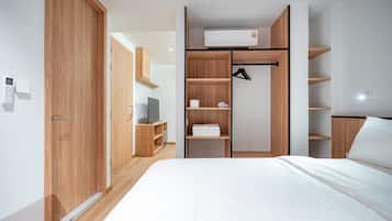 Un dormitorio moderno con cama, armario empotrado y televisor.