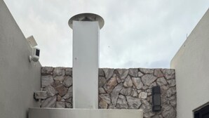 A stone wall with a built-in grill and a chimney. - Casa Oasis Boutique (Hermosillo)