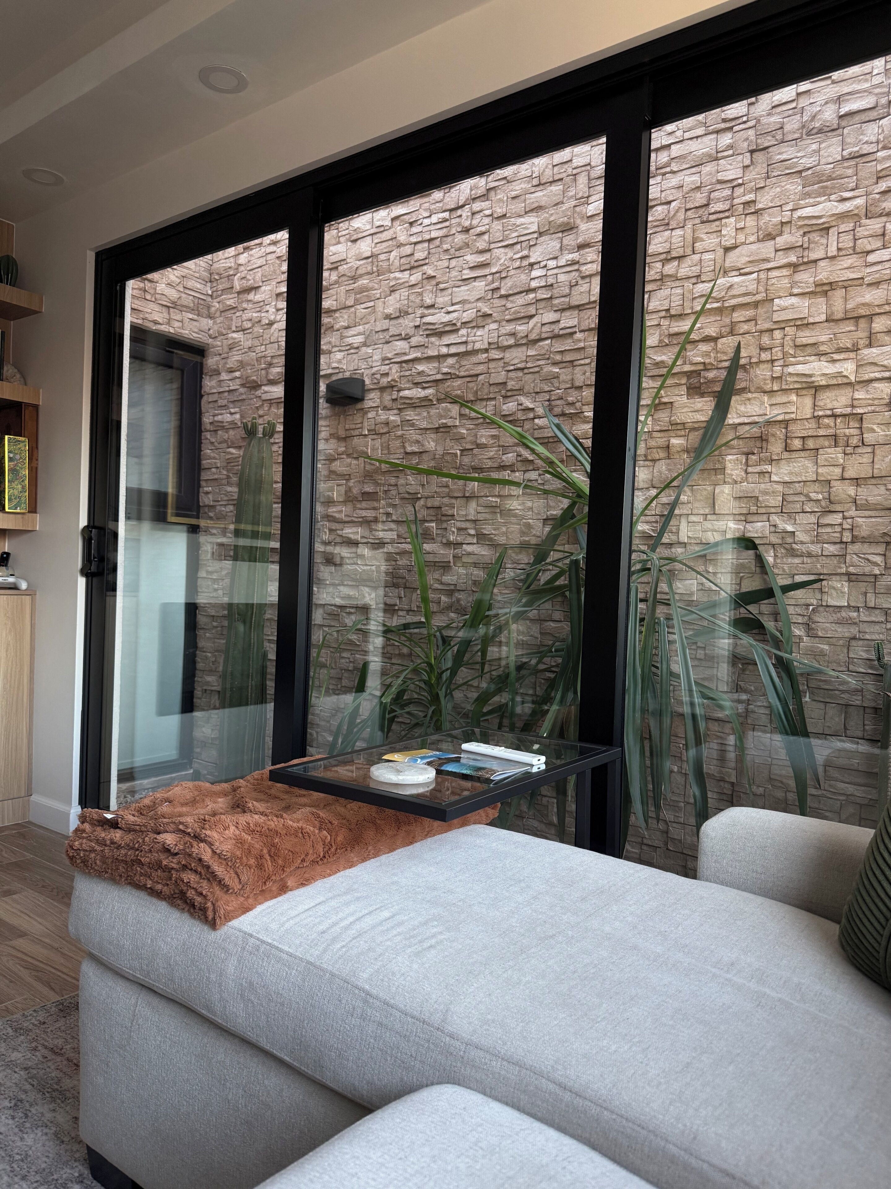 Una sala moderna con pared de piedra, una mesa de centro de vidrio y un sofá cómodo.