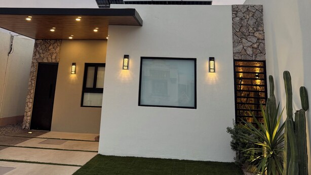A modern house with a solar panel, a stone accent wall, and a well-maintained lawn. - Casa Oasis Boutique (Hermosillo)