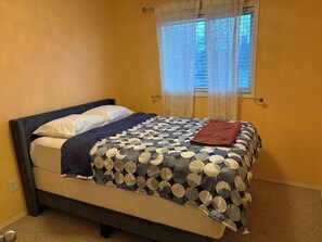 Uma cama com colcha estampada, um travesseiro e um cobertor.