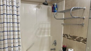 A bathroom with a bathtub, toilet, and sink. There is a shower curtain, a towel rack, and a potted plant. - 
Holiday Home in West Edmonton (Edmonton)
