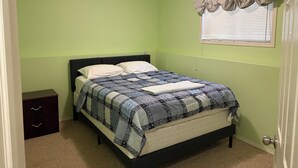 A bedroom with a bed, a nightstand, a dresser, and a window with blinds. - 
Holiday Home in West Edmonton (Edmonton)