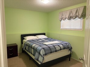 A bedroom with a bed, a nightstand, a dresser, and a window with blinds. - 
Holiday Home in West Edmonton (Edmonton)