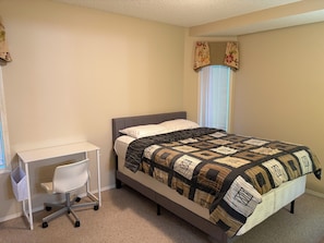 Ein Schlafzimmer mit einem Bett, einem Schreibtisch und einem Sessel.
