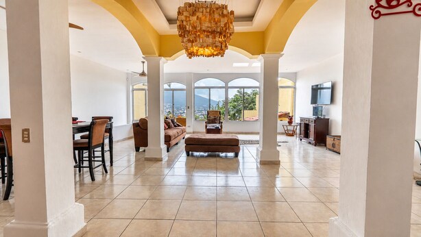 A spacious living area with a large sofa, a dining table with chairs, and a chandelier. - Skyline & Volcano San Salvador (SAN SALVADOR)