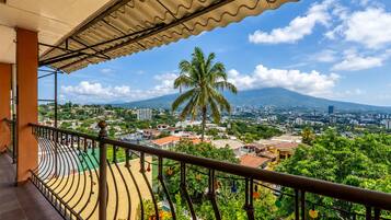 Uma varanda com vista para um horizonte urbano, palmeiras e uma montanha.