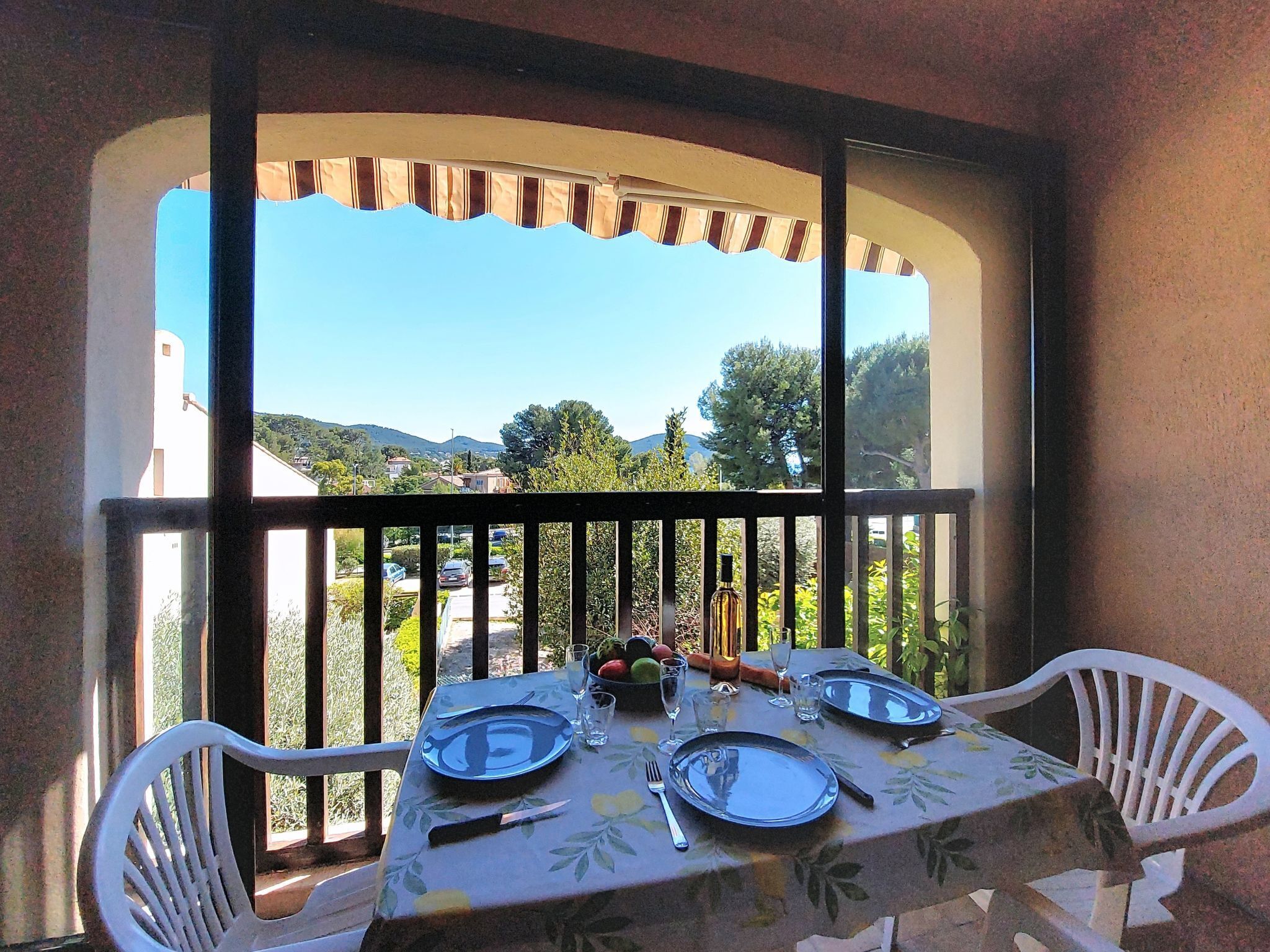 A balcony with a table set for two, overlooking a scenic landscape.