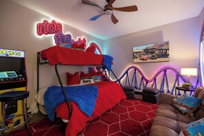 A bedroom with a bunk bed, arcade games, a ceiling fan, and a wall-mounted TV. - Resort Cabin > Golf Cart! > Hot Tub > Lazy River > Indoor Pool > Shuffleboard (Hollister)