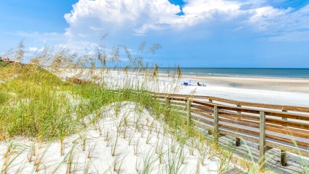 Ein Strand mit einer Holzlattenverkleidung und Sanddünen.