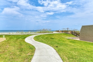 A curved concrete pathway leading to a beach area with a wooden fence and a building. - First Floor, Oceanfront, Direct Beach Access, Pristine Pool, Boat Ramp, Dock, $300 in Free Tickets! (St. Augustine)
