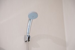 A chrome showerhead with a flexible hose, mounted on a wall. - GuestReady - Studio AR (São Mamede de Infesta)