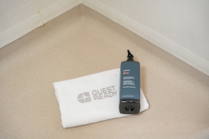A black hair care product on a white towel with the text 'GUEST READY' on it. - GuestReady - Studio AR (São Mamede de Infesta)