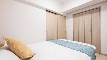 A bedroom with a bed, pillows, a blue blanket, and wooden wardrobes.